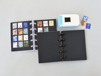 Black disc-bound notebook with colorful stamp designs on a gray background