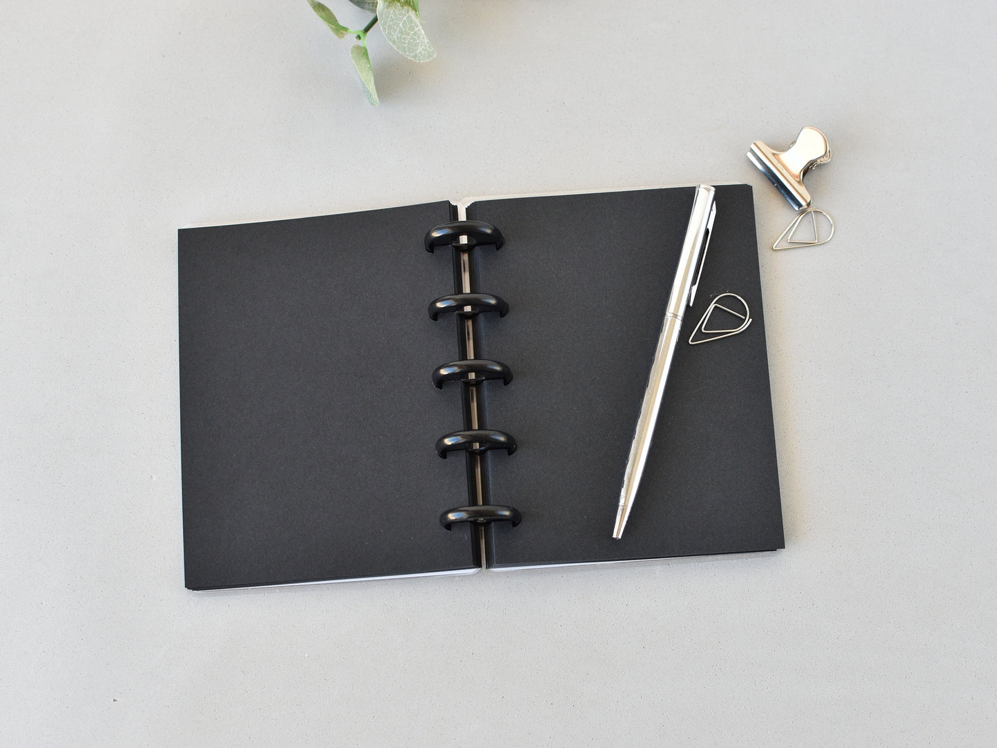 Black pages notebook with a pen on a light gray surface