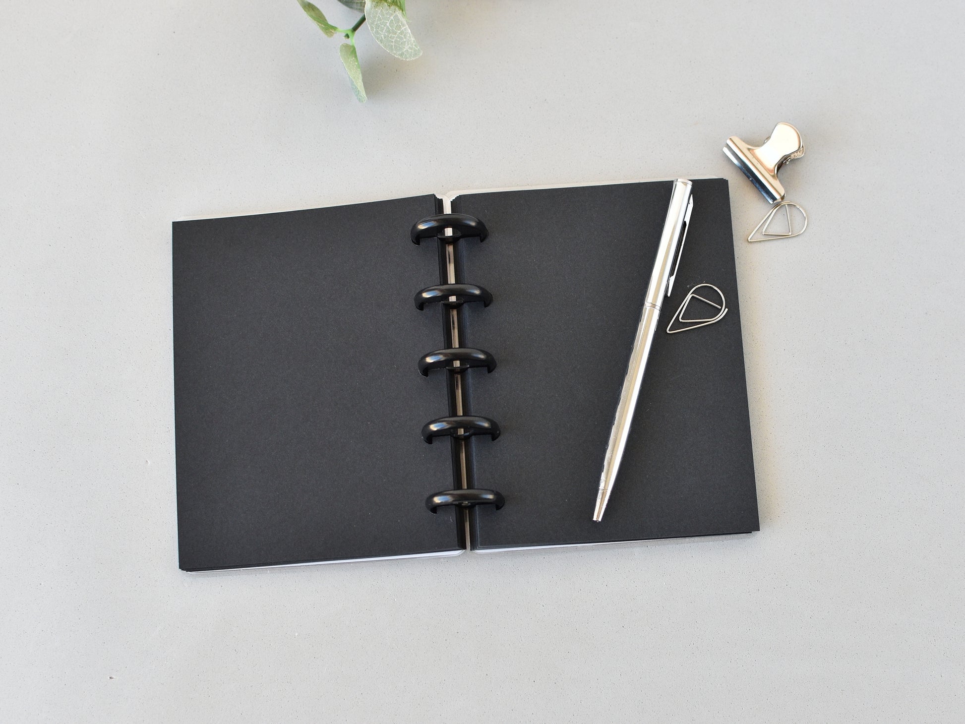 Black pages notebook with a pen on a light gray surface